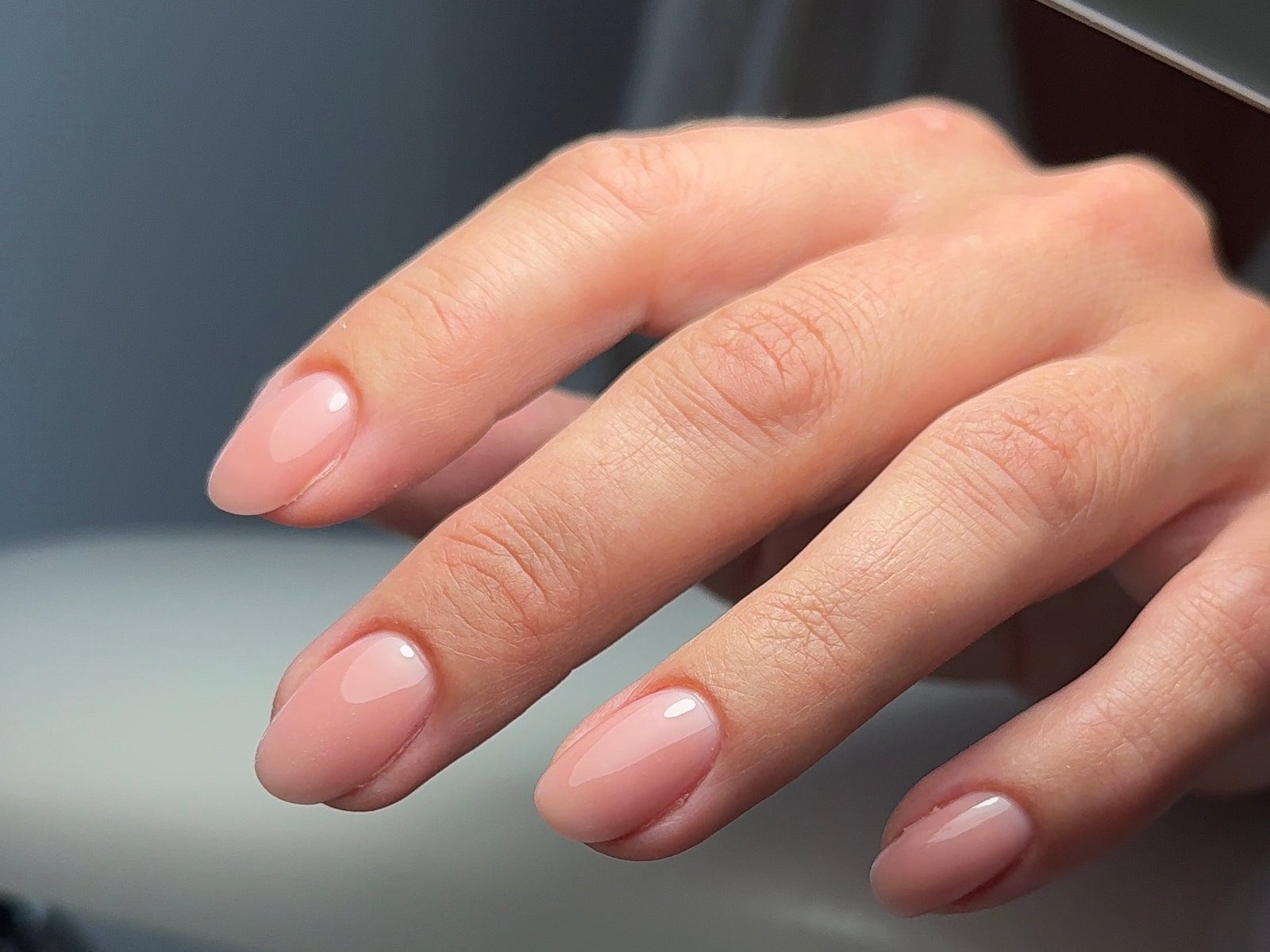Nude gellak op ovale nagels, de hand op de handsteun van de lamp